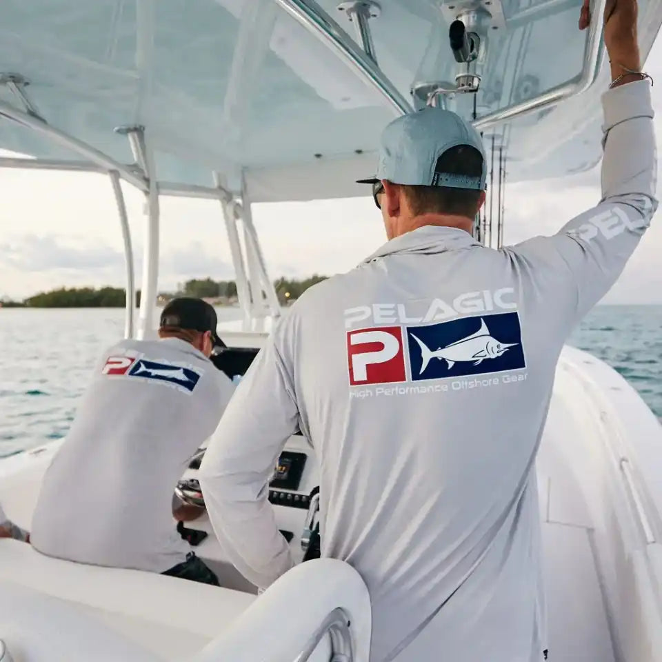 Two people wearing white Pelagic-branded shirts on a boat.